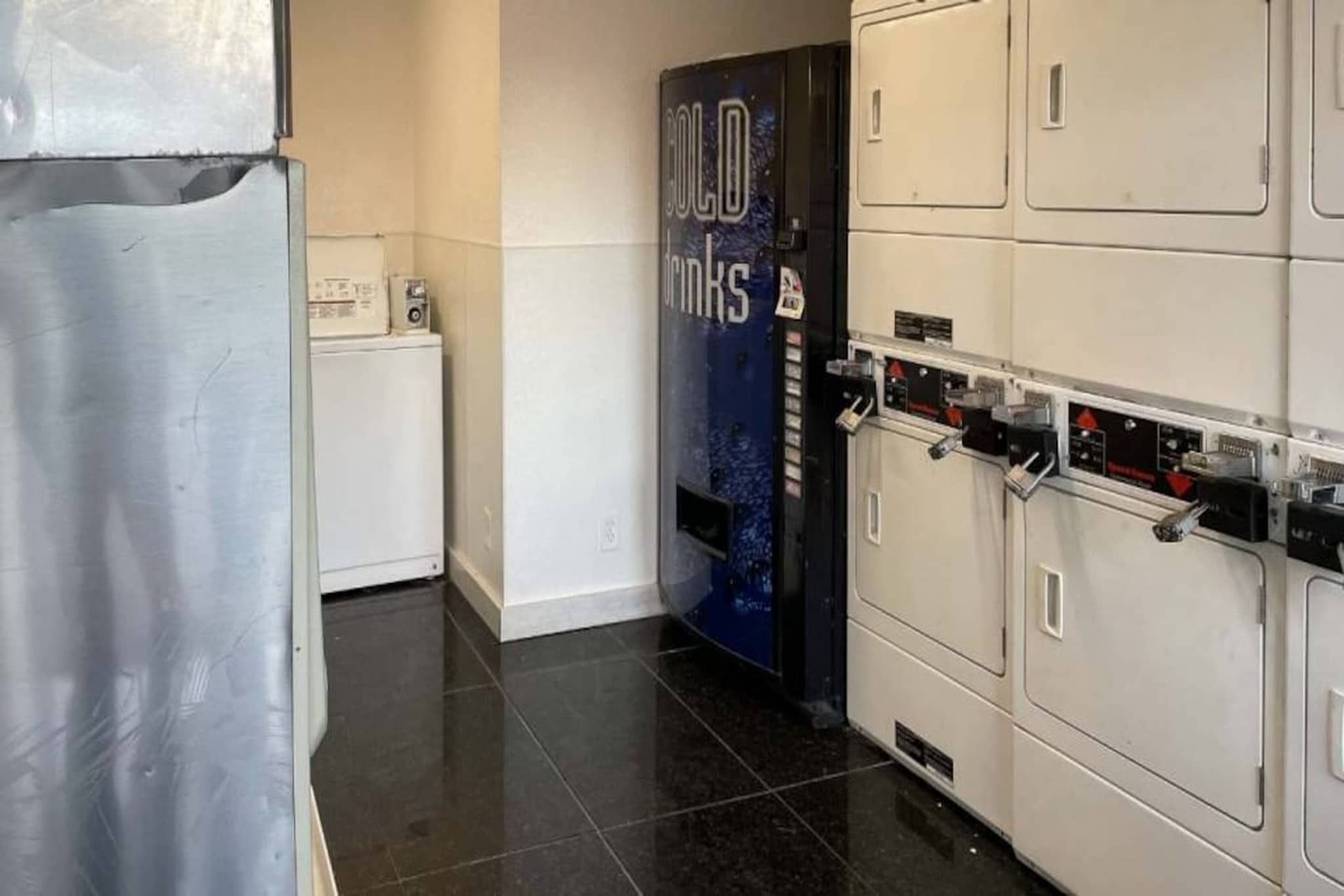 A laundry room with a washing machine, dryers, and a blue sign with text.
