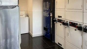 A laundry room with a washing machine, dryers, and a blue sign with text.