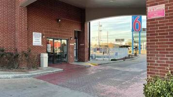 A brick building with a clear entrance, a parking lot, and a large blue sign with the number 6.