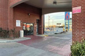 A brick building with a clear entrance, a parking lot, and a large blue sign with the number 6. - 2 Full Beds | Smoking, Kitchen (Houston)