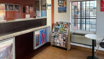 Zona de recepción de un hotel con mostrador, un atril para revistas y una ventana con vistas.