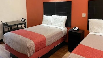 Una habitación de hotel con una cama, una mesita de noche, una silla y una pequeña mesa.