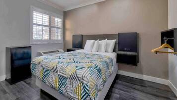 A modern bedroom with a large bed, a TV, and a window.