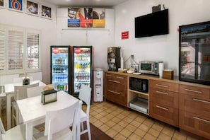 Une cuisine compacte équipée d’un réfrigérateur, d’un four à micro-ondes, d’une machine à café et d’un petit coin repas avec une table et des chaises.