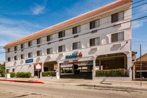 A motel with a red-tiled roof, multiple windows, and a sign indicating it is number 6.