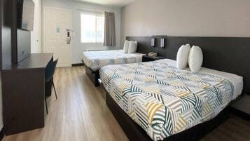 A hotel room with two beds, a desk, and a chair.