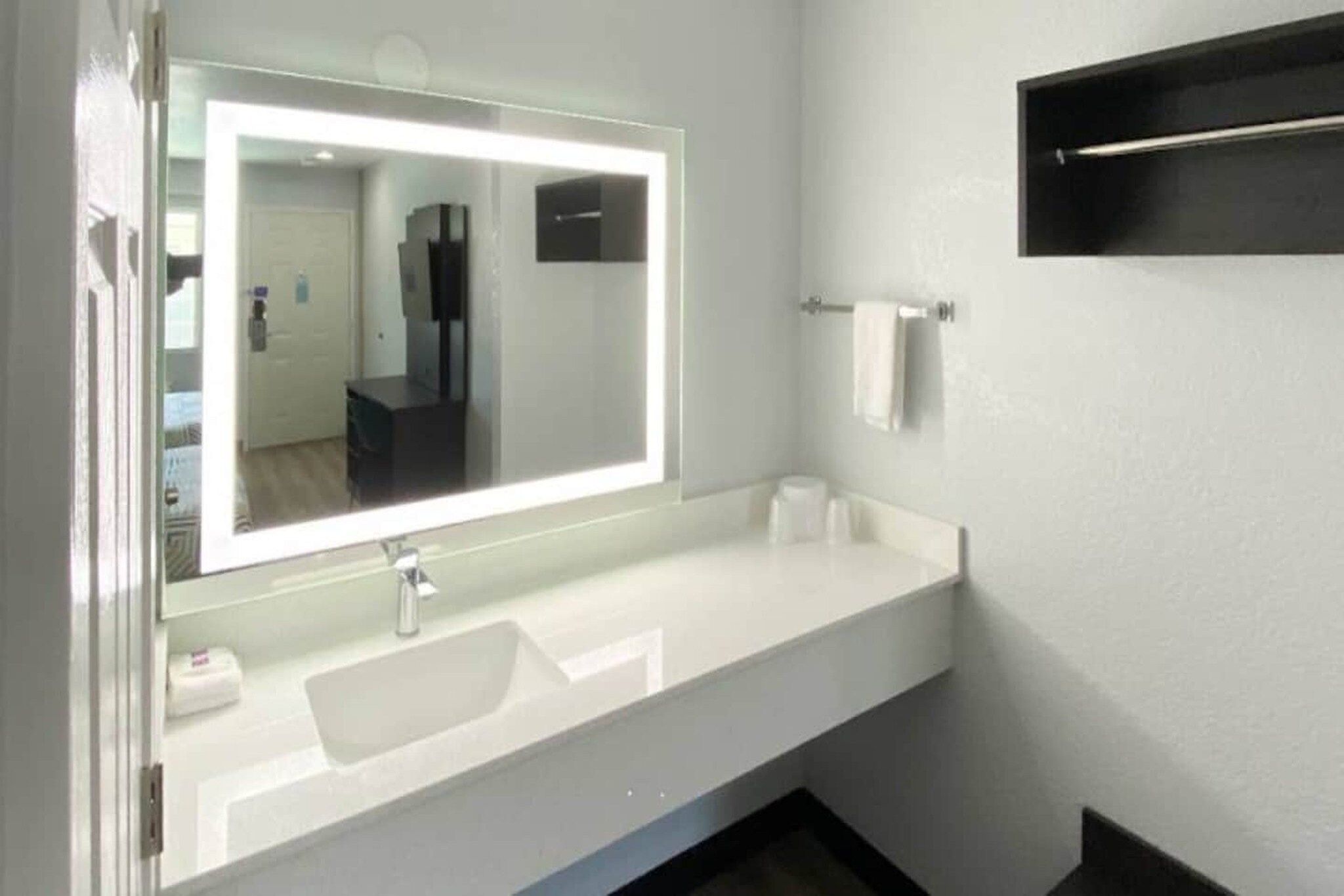 A bathroom with a white sink, a mirror, and a towel rack.