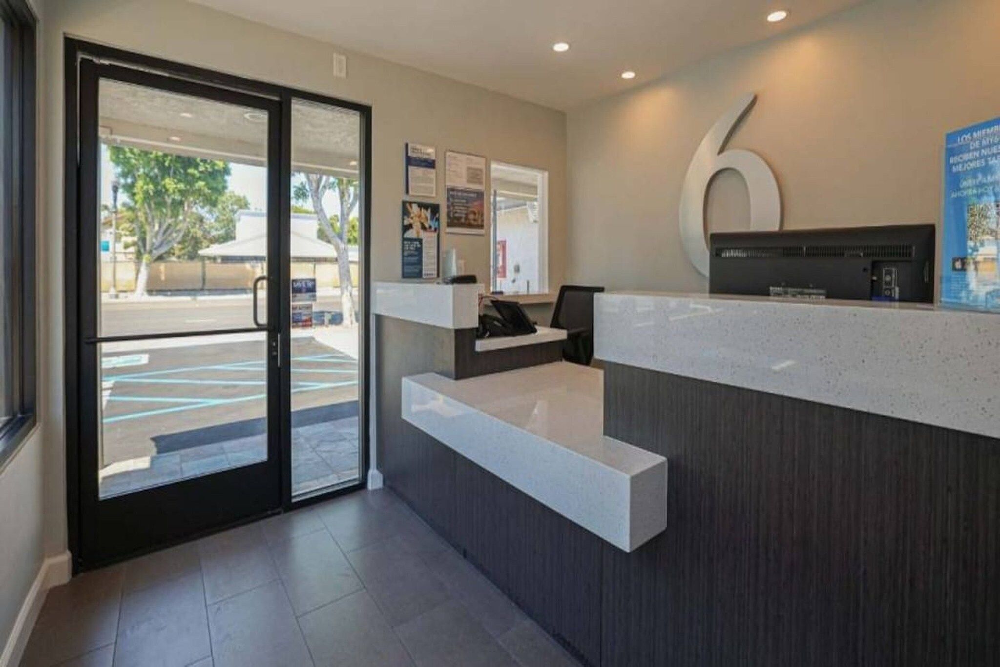 A reception area with a glass door entrance, a reception desk, and a large number '6' sign on the wall.