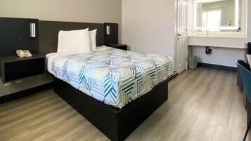 A hotel room with a bed, bedside table, and a mirror.