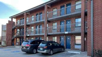 A multi-story brick building with a parking lot. There are two cars parked in the lot.