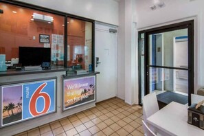 Un espace d’accueil d’hôtel comprenant un comptoir, un téléviseur et un panneau indiquant l’emplacement d’un motel situé à proximité.