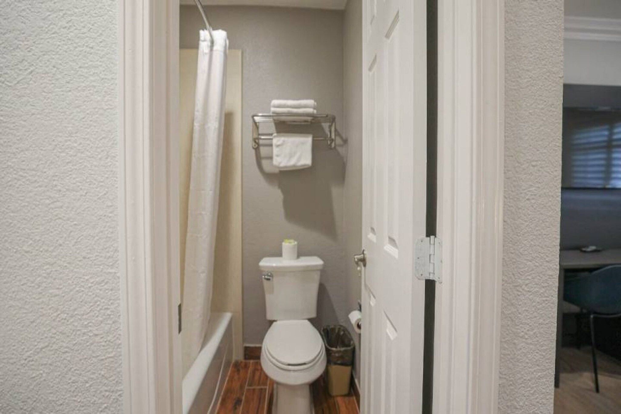 A narrow bathroom with a toilet, a towel rack, and a shower curtain.
