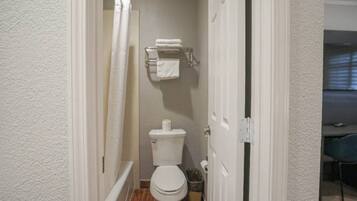 A narrow bathroom with a toilet, a towel rack, and a shower curtain.