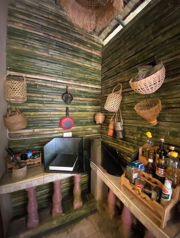A kitchen with a rustic design, featuring a wooden wall, hanging baskets, and a variety of kitchen utensils and appliances.