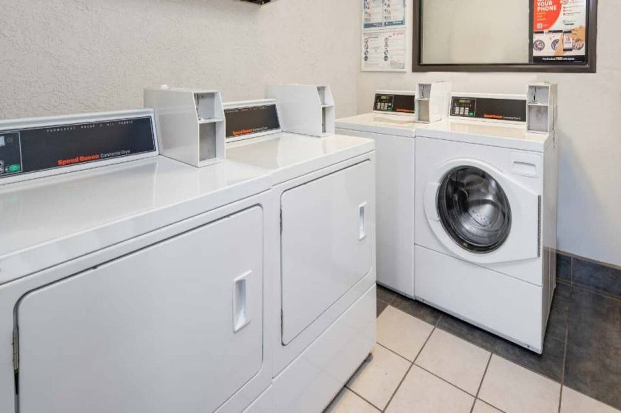 A laundry facility with a front-loading washing machine and a dryer, equipped with digital control panels.