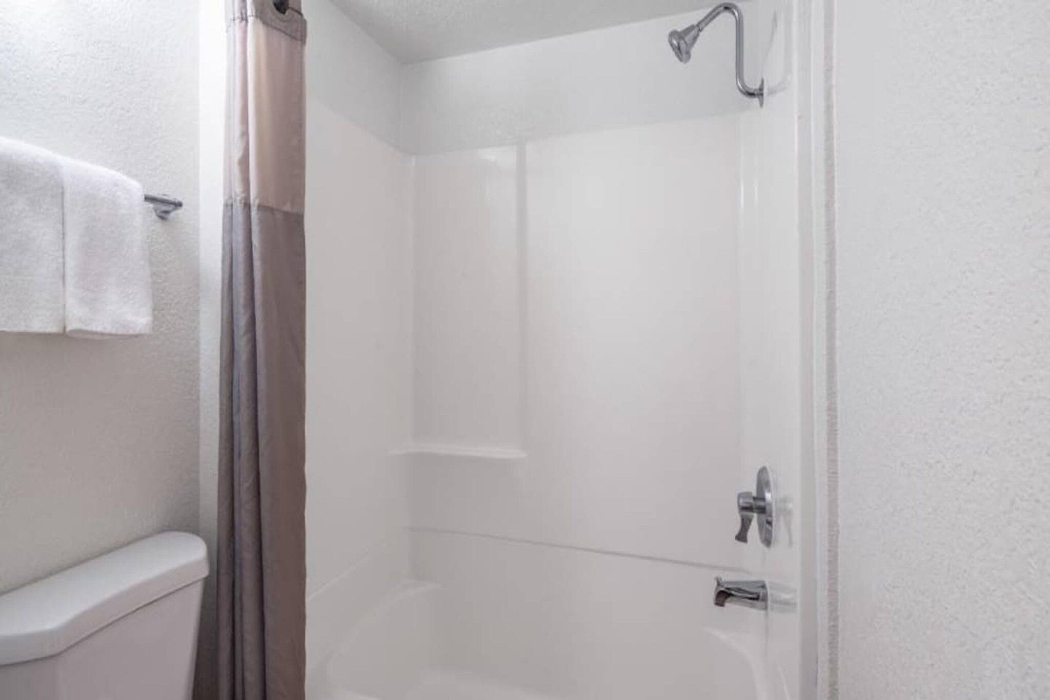Un baño con ducha, inodoro y perchero para toallas.