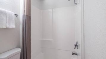 Un baño con ducha, inodoro y perchero para toallas.
