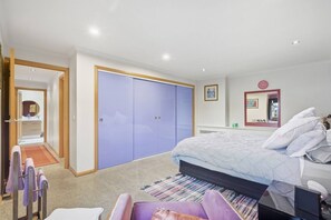 A bedroom with a bed, a wardrobe, a mirror, and a bathroom visible through an open door. - Barber`s Hyde | 2BR, Walk to Cafés & Waterfront (Lindisfarne)