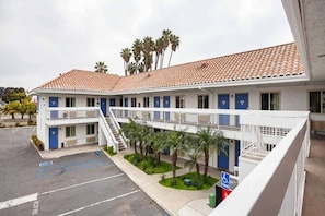 A motel with a two-story structure, a parking lot, and a sign indicating a handicapped parking space.