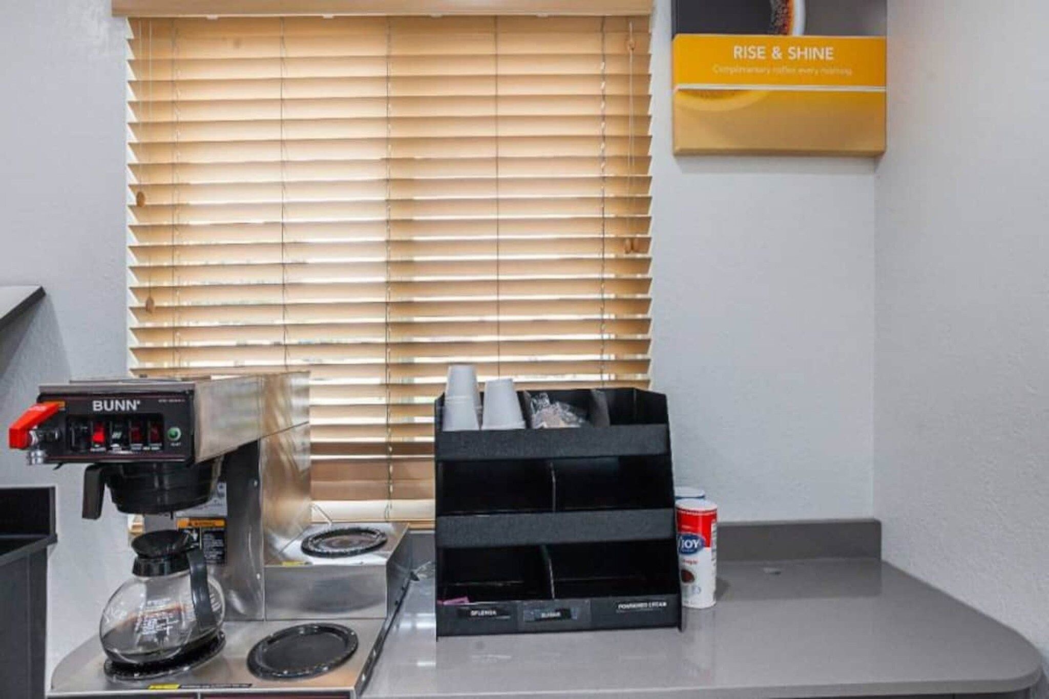 A coffee station with a Bunn espresso machine, a coffee grinder, and a can of milk.