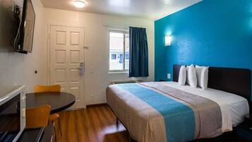 A hotel room with a bed, a desk, and a chair.