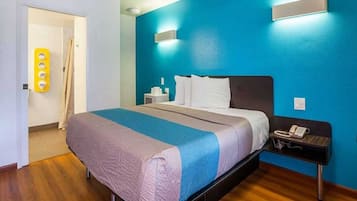 Una habitación de hotel con una cama, una mesita de noche y un teléfono instalado en la pared.