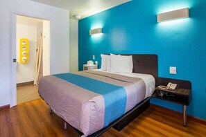Habitació d'hotel amb llit, taula de nit i un telèfon fixat a la paret.