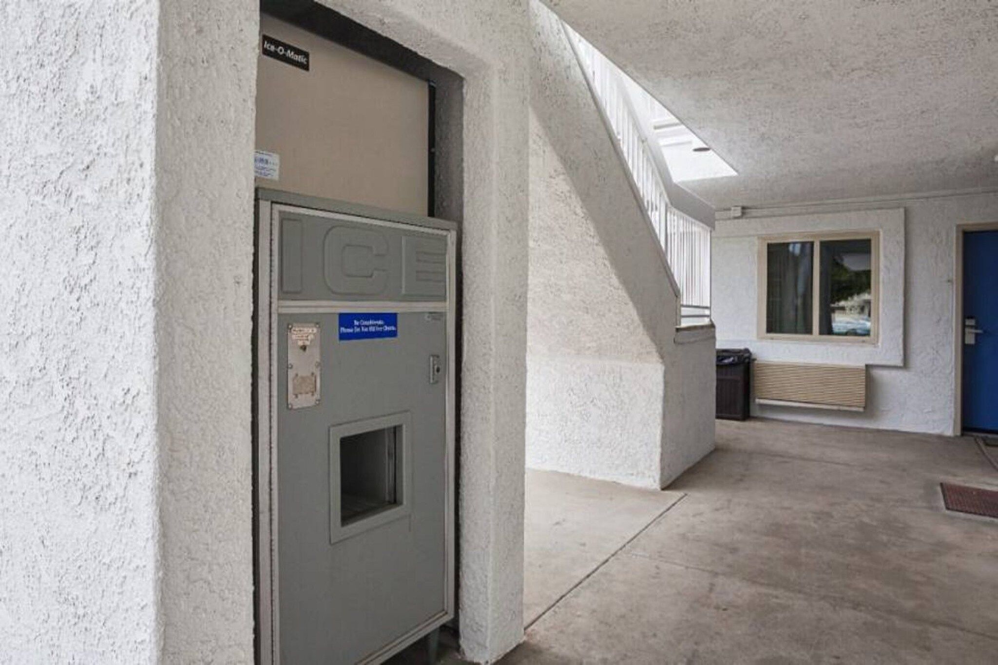 A building entrance with a metal door, a staircase, and a window.