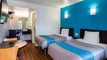 Une chambre d’hôtel avec deux lits, un bureau et une chaise.