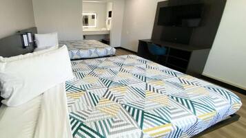 A hotel room with a bed, a TV, and a seating area.