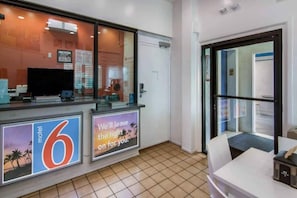 Un espace d’accueil d’hôtel comprenant un comptoir, un téléviseur et un panneau indiquant l’emplacement d’un motel situé à proximité.