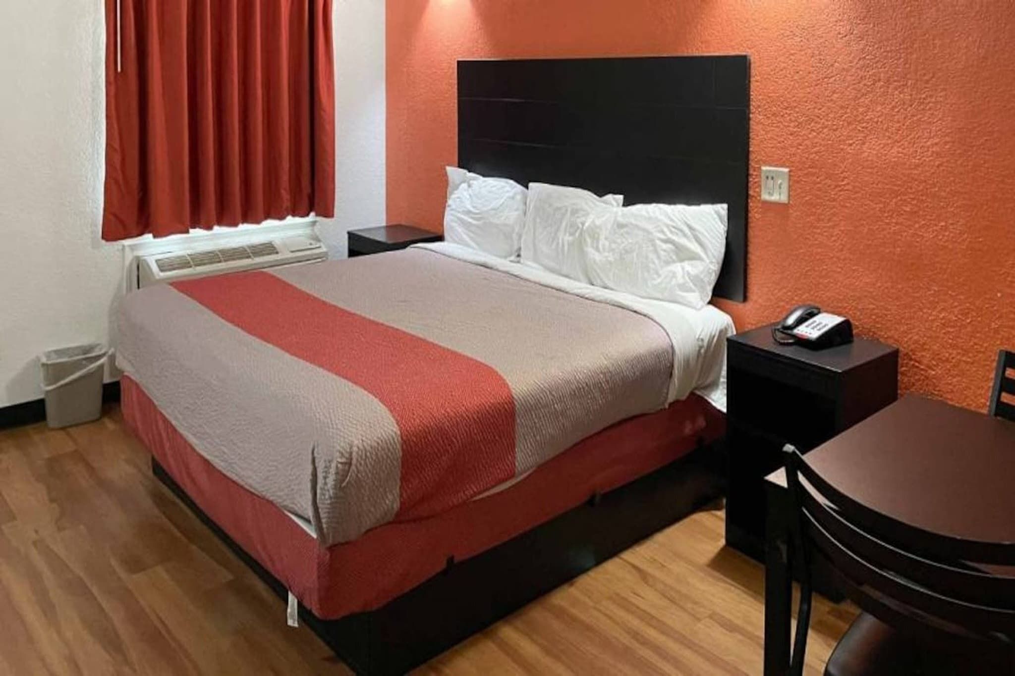 Ein Hotelzimmer mit einem Bett, Nachttischen, einem Sessel und einem kleinen Tisch.