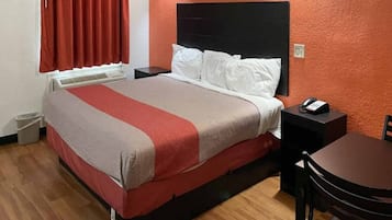 Ein Hotelzimmer mit einem Bett, Nachttischen, einem Sessel und einem kleinen Tisch.