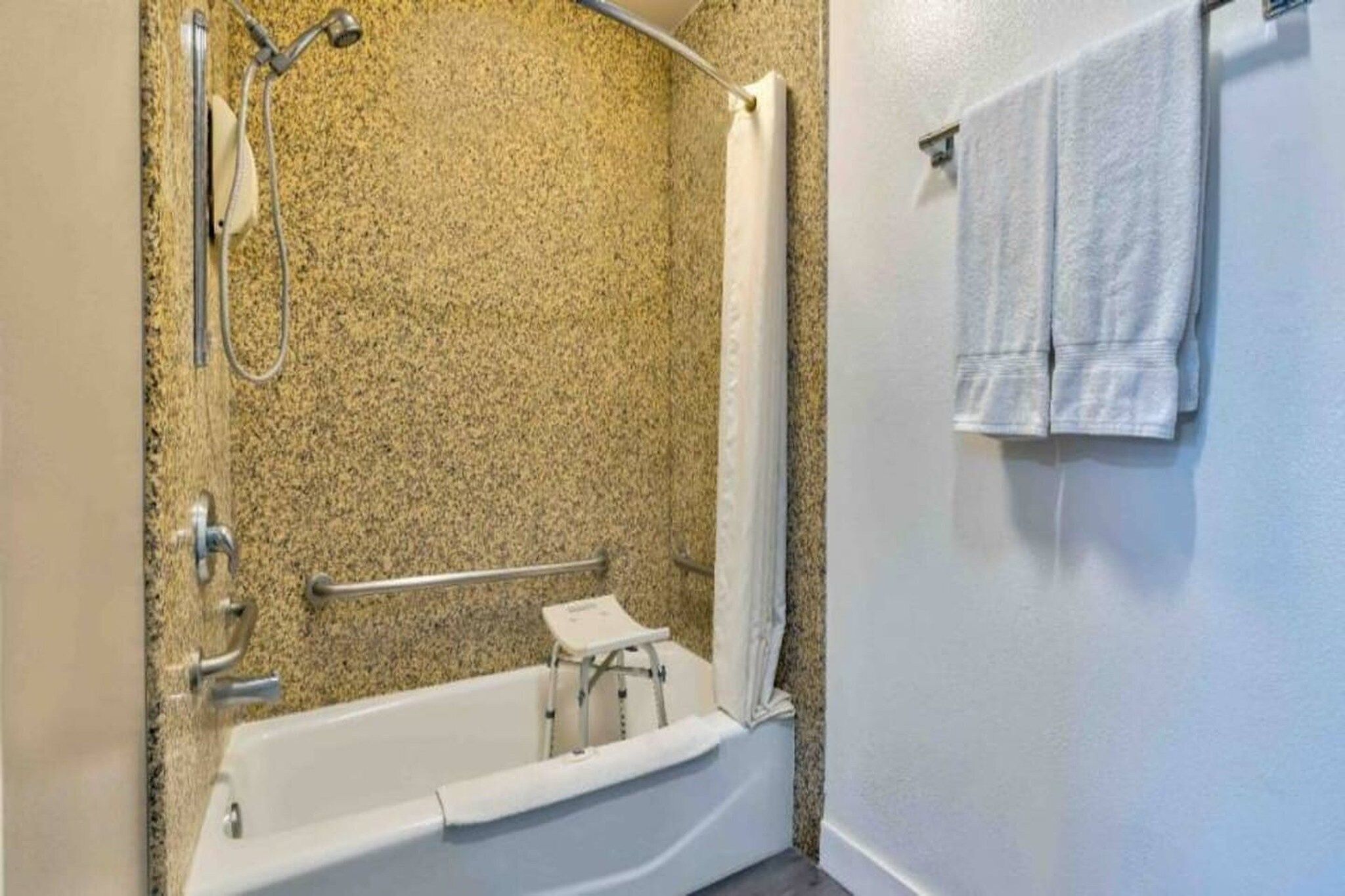 Ein Badezimmer mit Badewanne, Dusche und einer Haltestange.