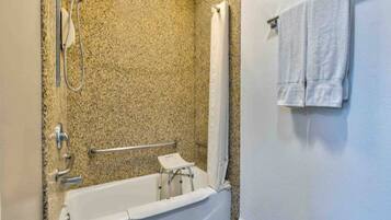 Ein Badezimmer mit Badewanne, Dusche und einer Haltestange.
