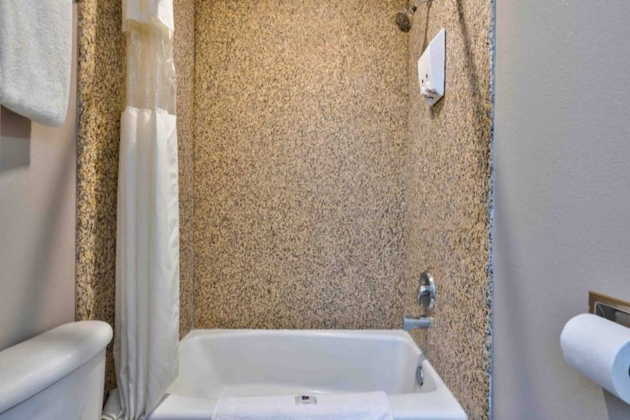 A bathroom with a bathtub, a toilet, and a shower curtain.