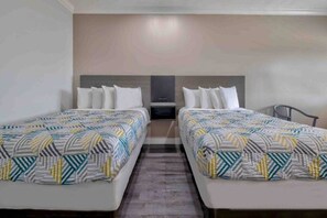 Una habitación de hotel con dos camas, una mesita de noche y una silla.