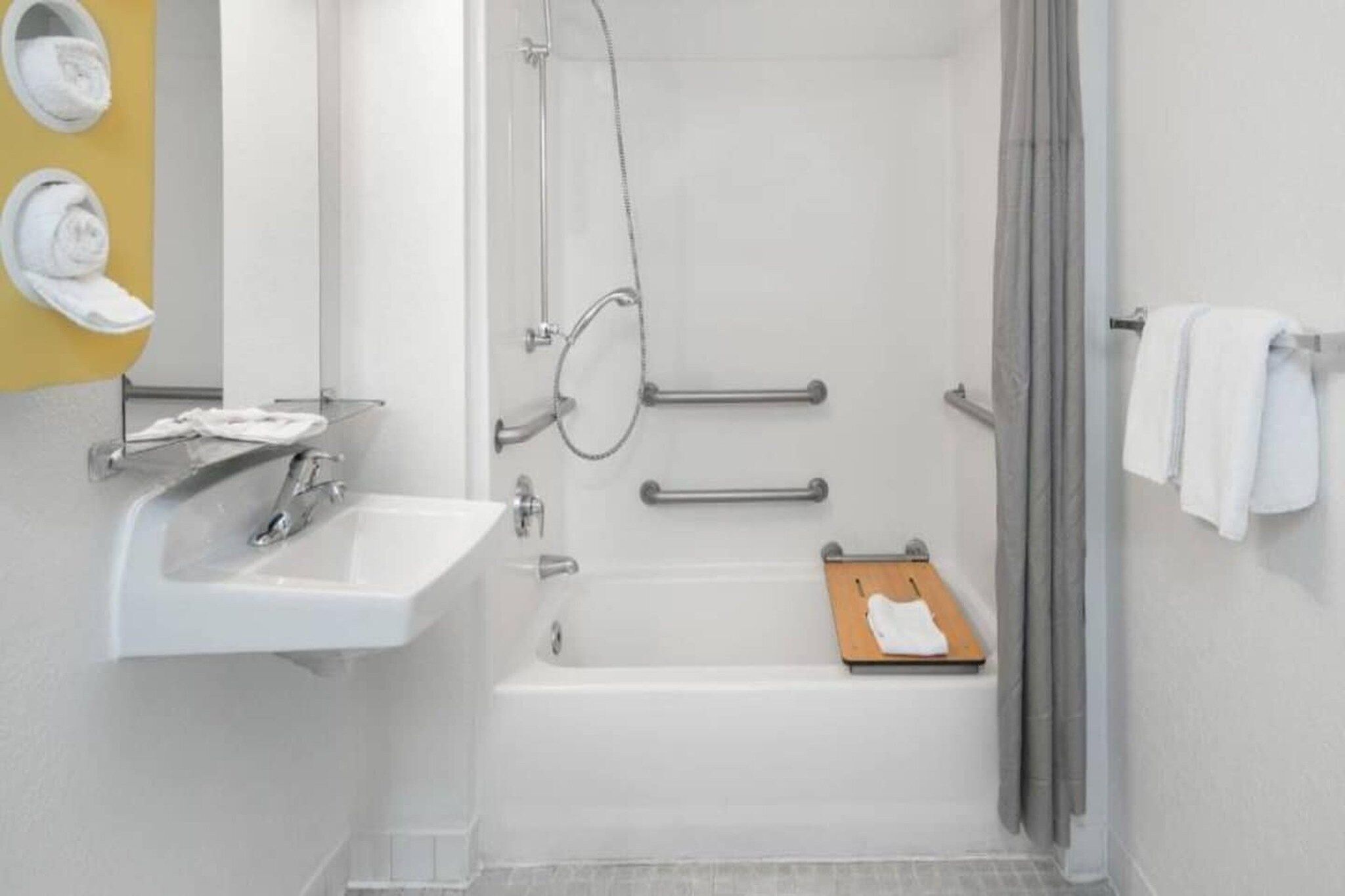 A bathroom with a white sink, a shower, and a towel rack.