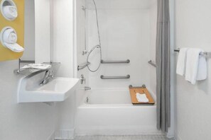 Un bagno con lavandino bianco, doccia e porta asciugamani.