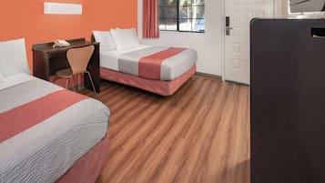 Una camera d'albergo con due letti, una scrivania, una sedia e una finestra con tende.