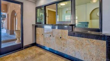 A reception area with a marble wall, a reception desk, and a door leading to an interior space.