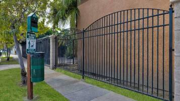 A fenced area with a pet waste station and a trash bin.