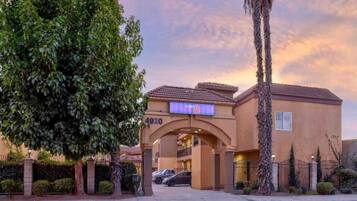 A hotel entrance with a large archway, a sign indicating the number 4920, and a parking area with cars.