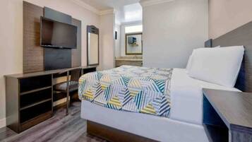 Une chambre d’hôtel équipée d’un lit, d’un bureau, d’une chaise, d’une télévision et d’un miroir.