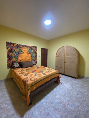 A room with a bed, a door, and a wall with a colorful tapestry. - Lakshmi bungalow at Yanui beach with a sea view (Phuket)