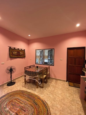 A dining area with a table, chairs, a fan, and a rug. - Lakshmi bungalow at Yanui beach with a sea view (Phuket)