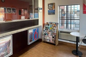 Un espace d’accueil comprenant un comptoir, un présentoir à magazines et une fenêtre donnant sur un paysage agréable.
