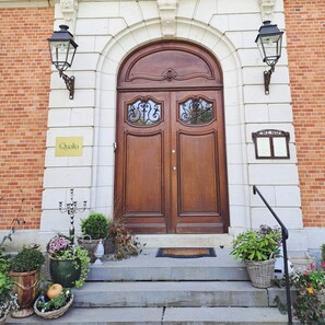 A wooden double door with decorative glass panels, a sign reading 'Qualia', and a brick wall. - The rest of the story of Little Château Peltzer (Verviers)