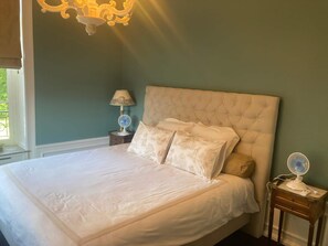 Una camera da letto con un letto grande, un comodino con una lampada e un ventilatore a muro.