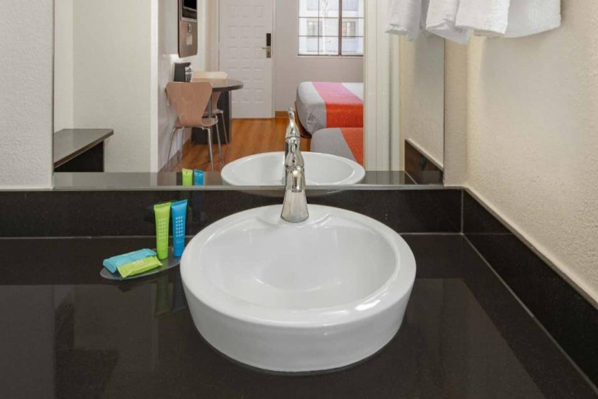 Een badkamer met een witte wastafel, een spiegel en toiletartikelen op het aanrecht.